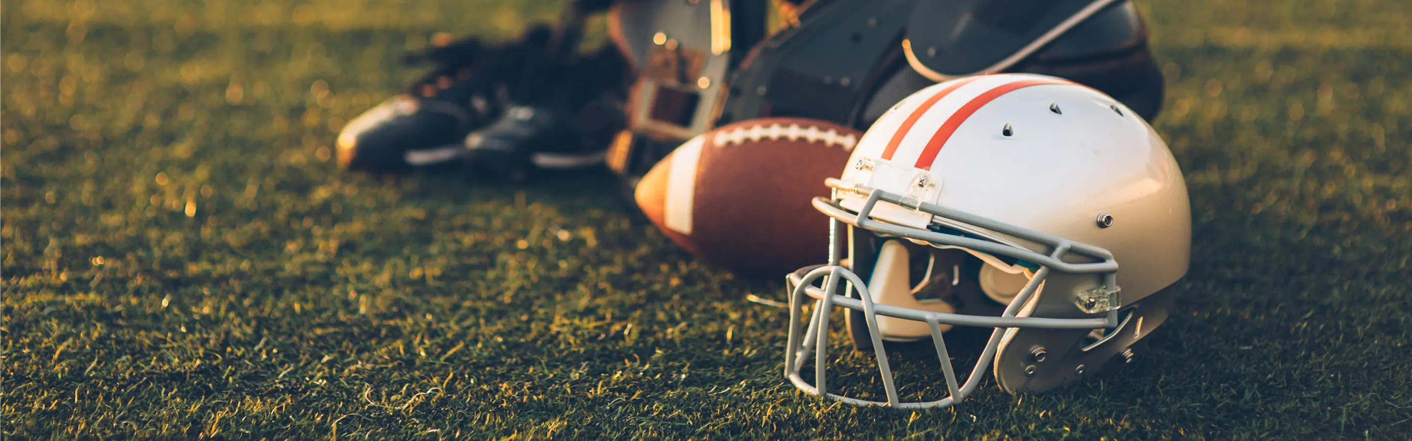 Football helmet and gear on grass field.