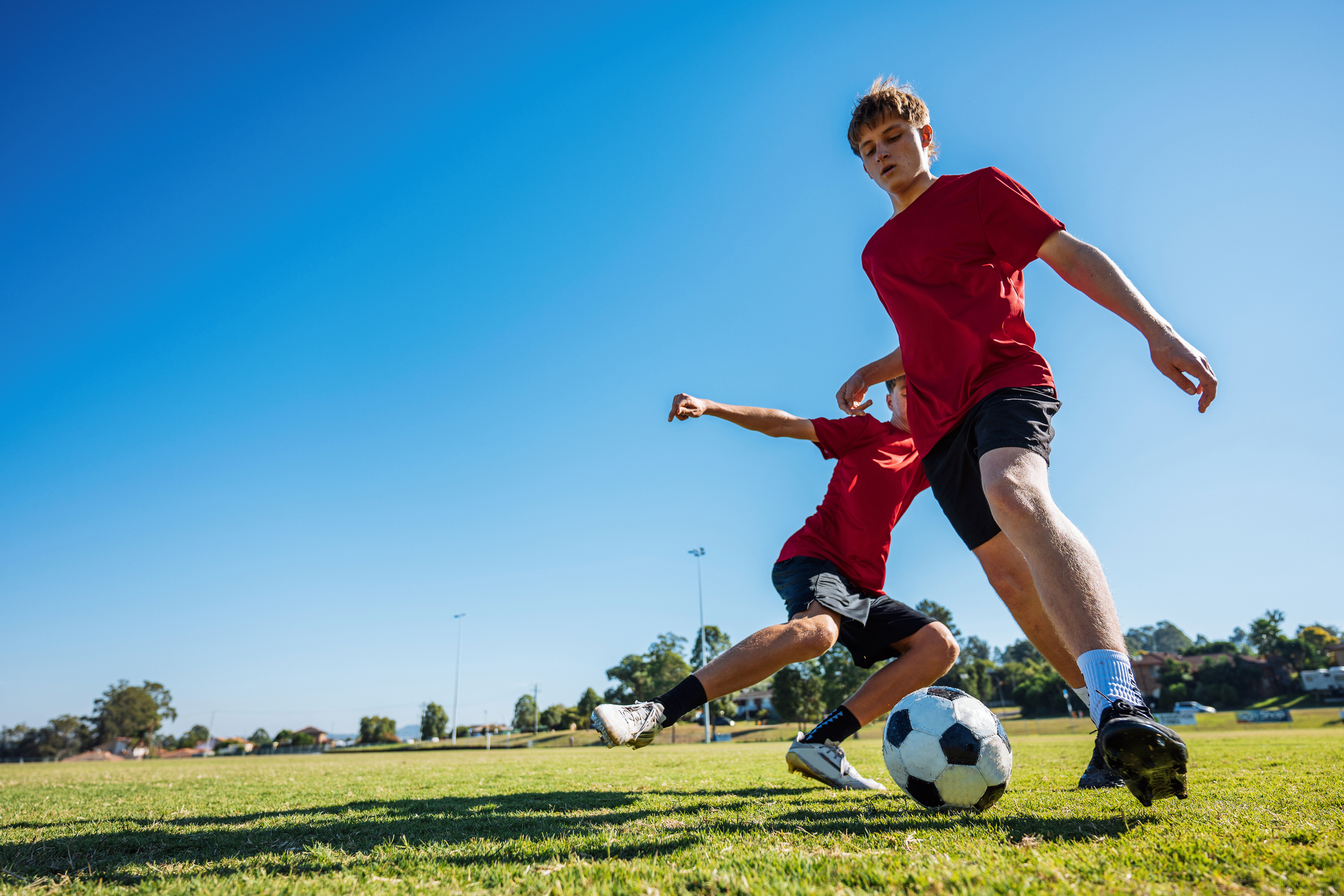 Two people playing soccer on grass field.