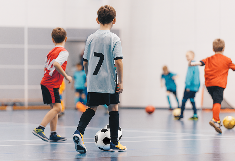 A diverse group of children playing soccer on a court, highlighting their excitement and teamwork during the game.